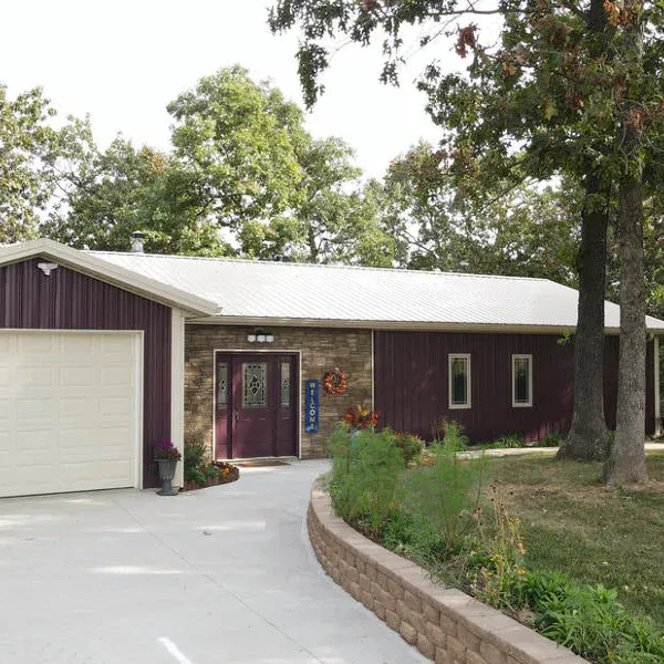 Burgundy steel ranch home with white metal roof, stone accents and attached garage