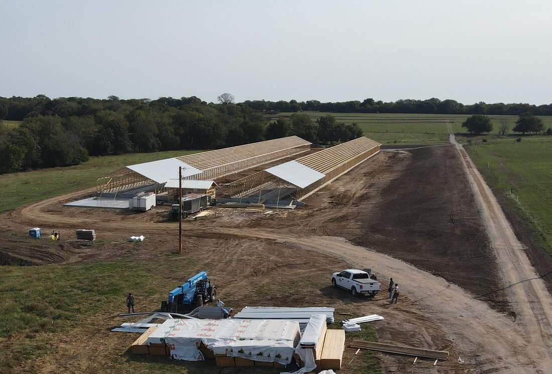 Pole building under construction with trusses set and steel panels staged on site