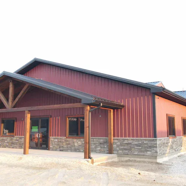 Burgundy steel commercial building with black metal roof, timber truss entry and stone wainscot