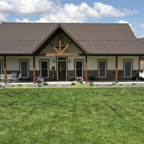 Cream steel ranch home with brown metal roof, timber posts, stone wainscot and long covered porch