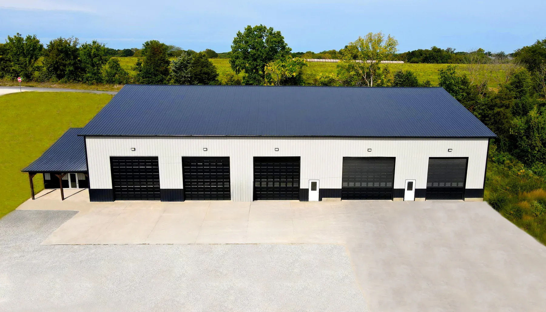 White steel commercial shop with black roof, black wainscot and five tall overhead doors